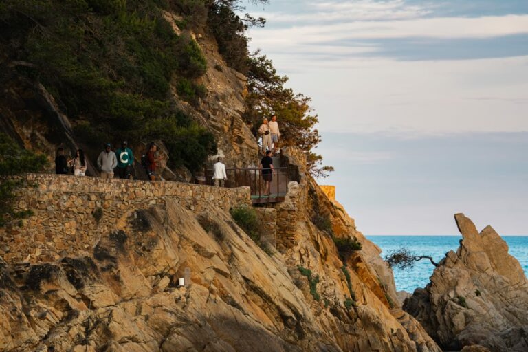 Gent caminant per la passera del camí de ronda, a l’alçada del Castell de Lloret