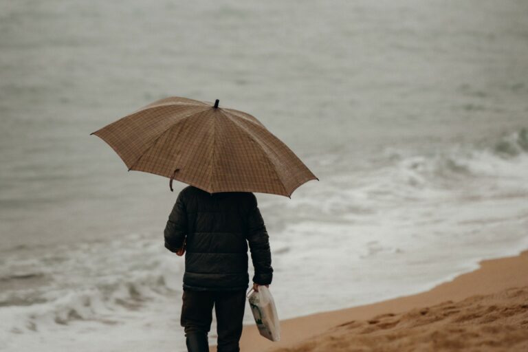Un home amb paraigües a la platja de Lloret