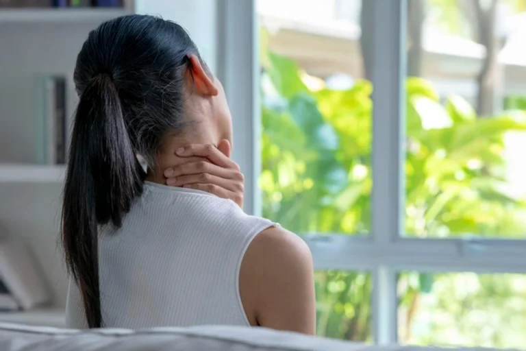 Dona amb dolor cervical agafant-se el coll amb la mà