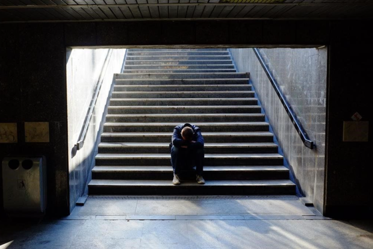 Un jove assegut a les escales de la boca del metro (El Periódico)