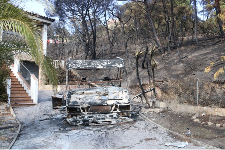 Una autocaravana calcinada en un jardí d'una casa a Lloret de Mar. Imatge del 13 de juliol del 2021. (Horitzontal)